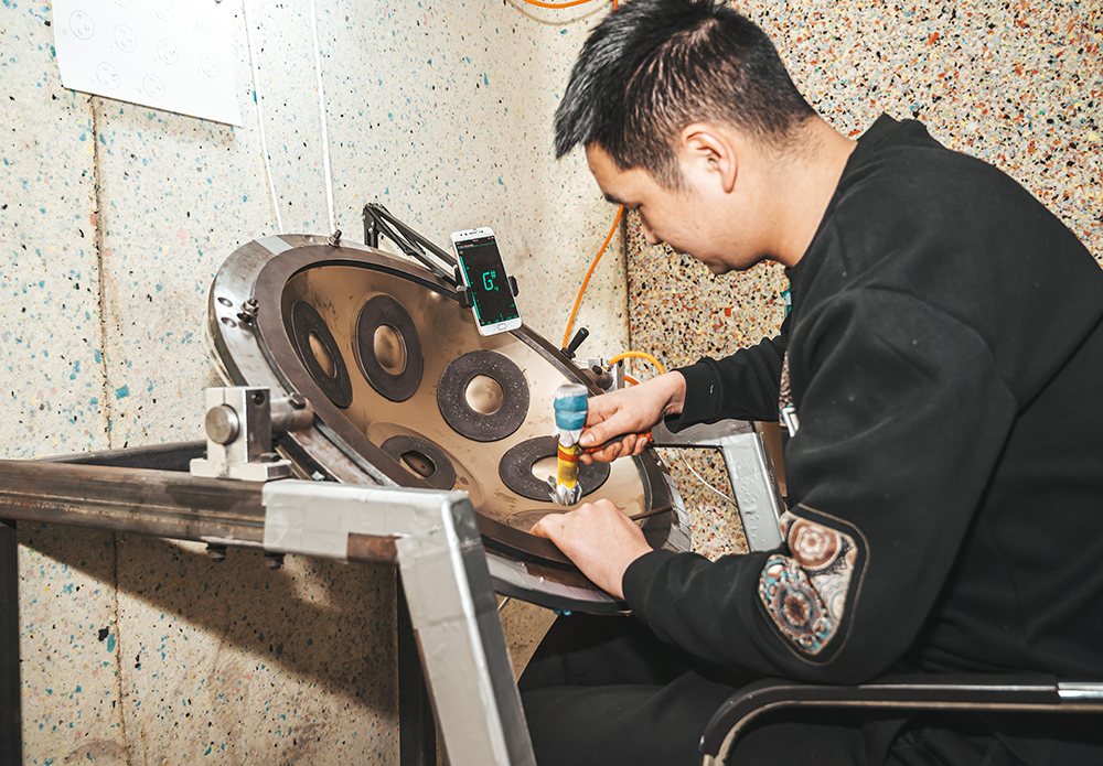 Experienced tuner shaping the notes of a handpan in the Linyi workshop